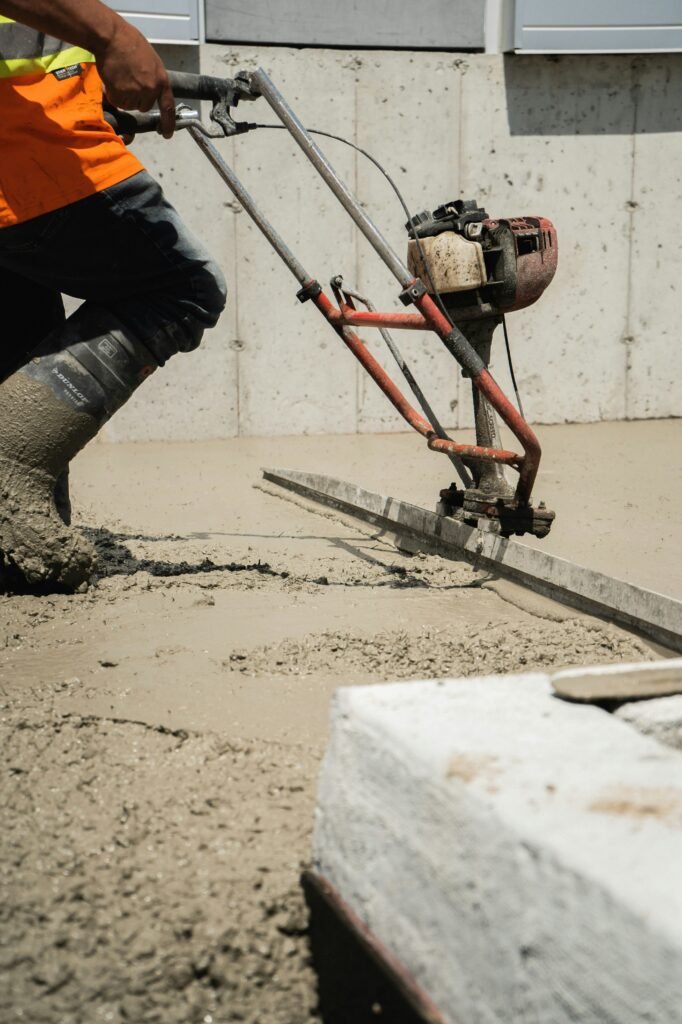 Professional concrete contractor leveling a fresh pour using a power screed on a residential project in Fort Wayne.