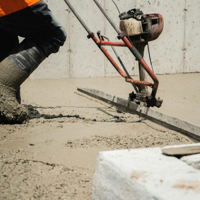 Professional concrete contractor leveling a fresh pour using a power screed on a residential project in Fort Wayne.